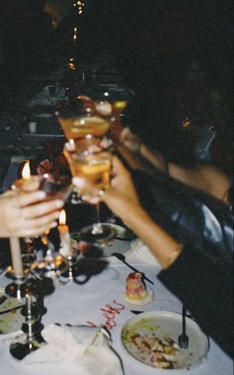 Glasses raised in a toast over a long candlelit table